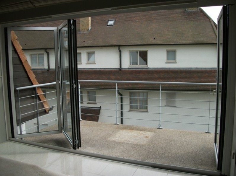 Black aluminum bifold glass doors fully opened connecting indoor living space to outdoor patio area