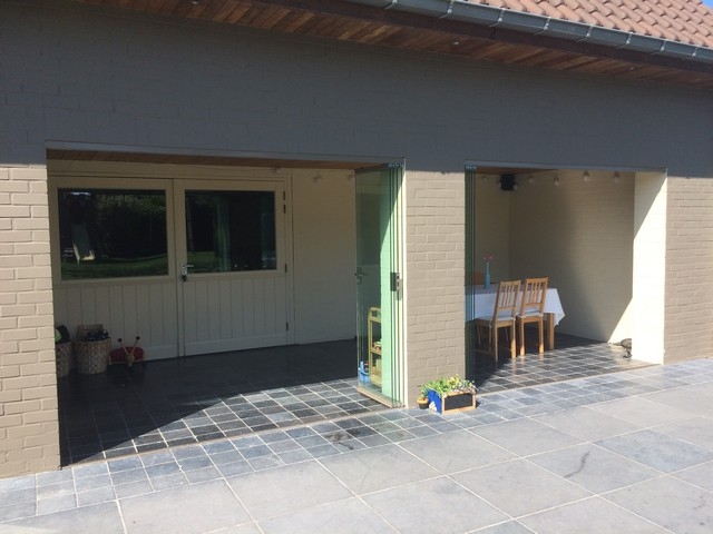 Black aluminum bifold glass doors fully opened connecting indoor living space to outdoor patio area
