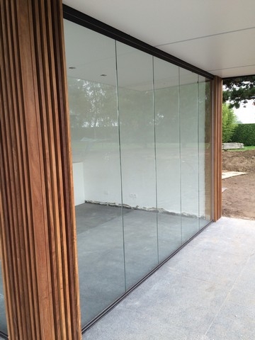 Black aluminum bifold glass doors fully opened connecting indoor living space to outdoor patio area